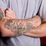 homem de braços cruzados tatuados