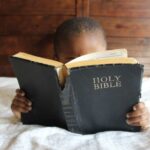 menino lendo a bíblia na cama