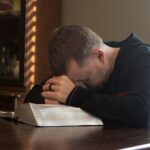 homem orando com a bíblia aberta em cima da mesma